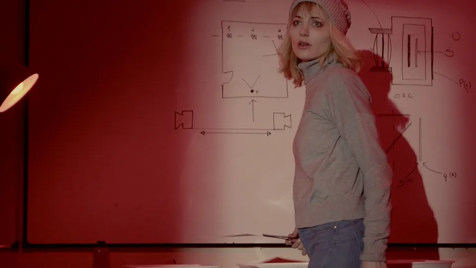 Heroine studying hand-drawn plans on a red whiteboard